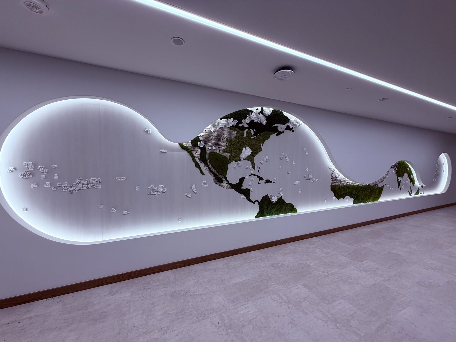 Cove lit world map wall in moss, metal, and keyboard key continents